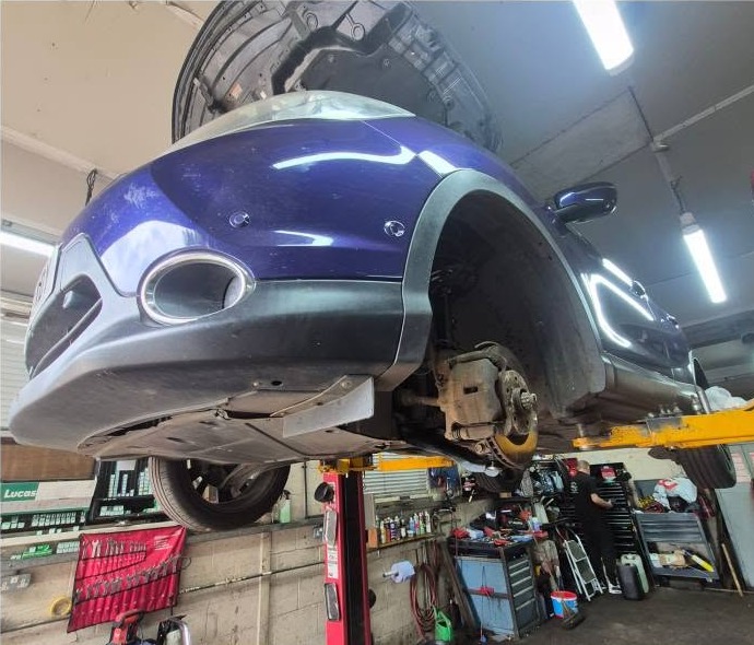 A blue car raised on the two-post lift in the Colkirk Motor Repairs workshop