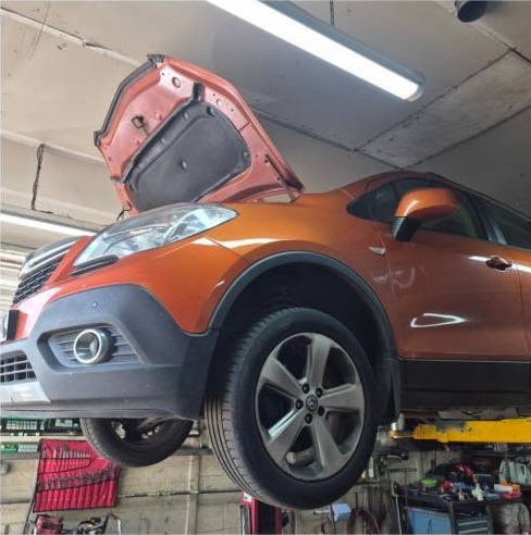 An orange SUV on the lift with its bonnet open